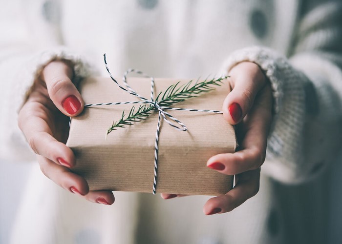 Woman's hands hold christmas or new year decorated gift box.